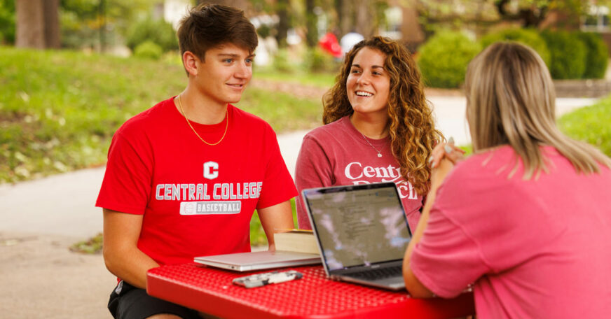 Central College students gathered outside at a picnic table.